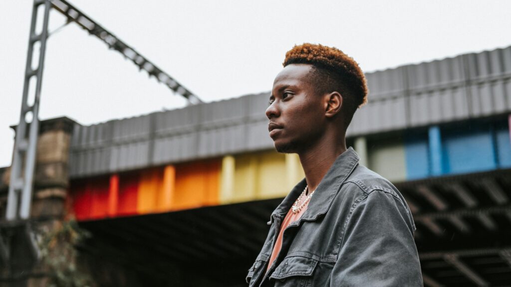 A person stands in front of a wall in rainbow colours in a seemingly industrial setting
