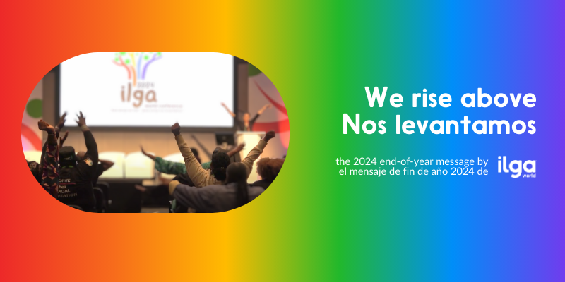 Colorful end-of-year graphic by ILGA World for 2024. The image features a rainbow gradient background transitioning from red to purple. On the left, a photo shows a group of people raising their hands in celebration at an ILGA event, with a blurred projection of the ILGA logo visible in the background. On the right, white text reads: 'We rise above / Nos levantamos.' Below, smaller text states: 'The 2024 end-of-year message by / el mensaje de fin de año 2024 de ILGA World.' The ILGA World logo is in the bottom right.