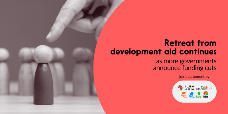 The photo shows a hand pointing a finger towards a pawn, which is in different colours that the other pawns around. Text reads: "Retreat from development aid continues s more governments announce funding cuts". The logos of ILGA World, Pan Africa ILGA, ILGA Asia, ILGA-Europe, ILGA-NAC, ILGA Oceania, ILGALAC are placed at the bottom right of the image