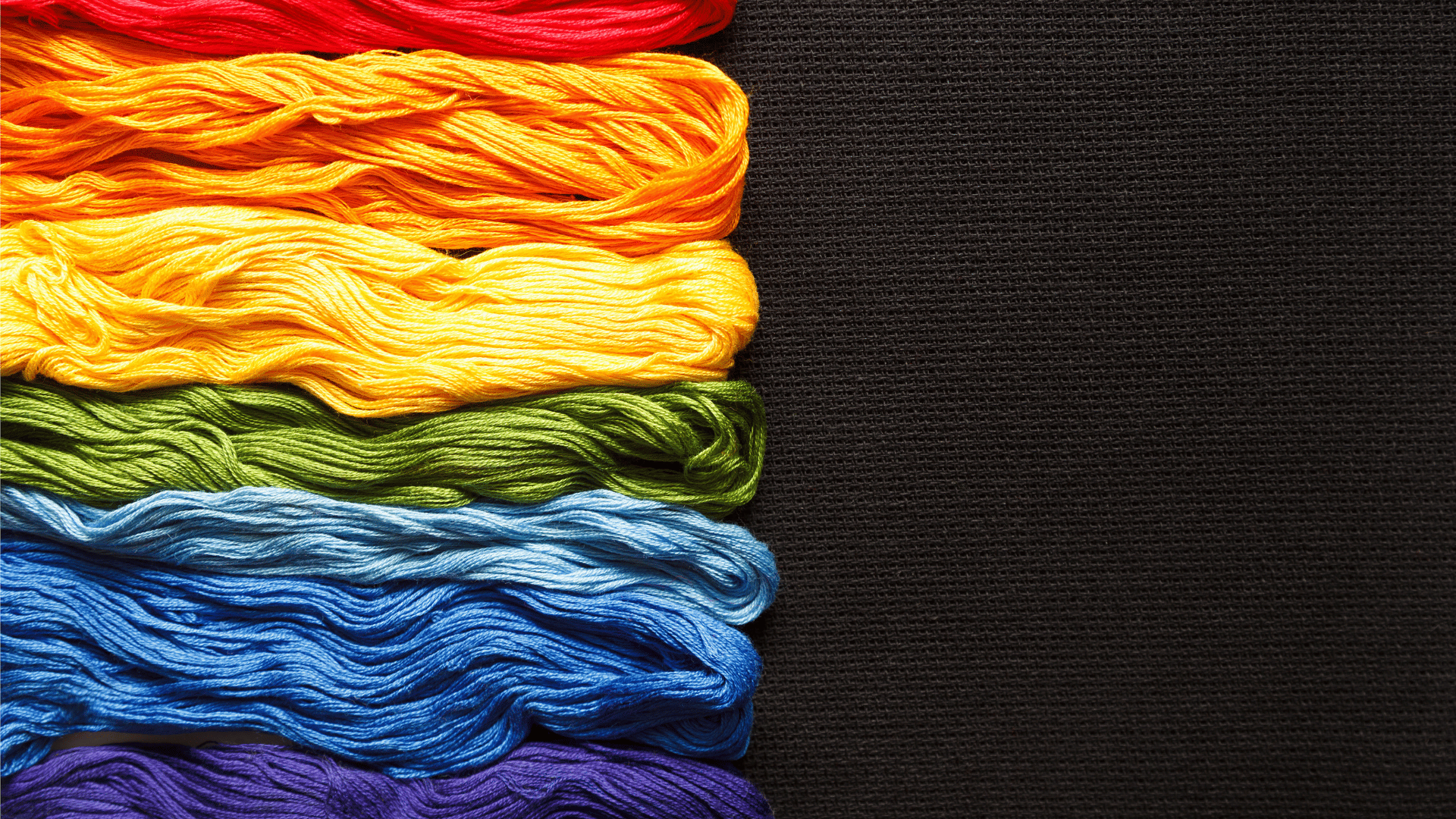 Rainbow colour threads on a black canvas