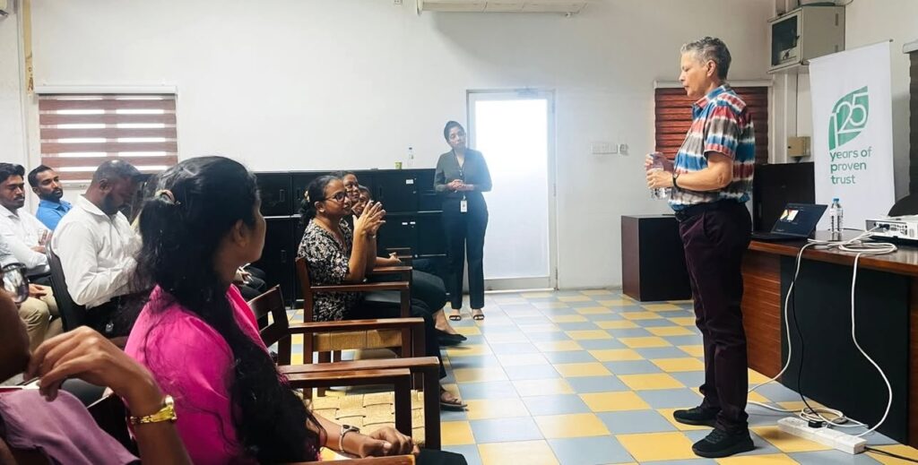 A woman with short hair delivers a training in front of a live audience