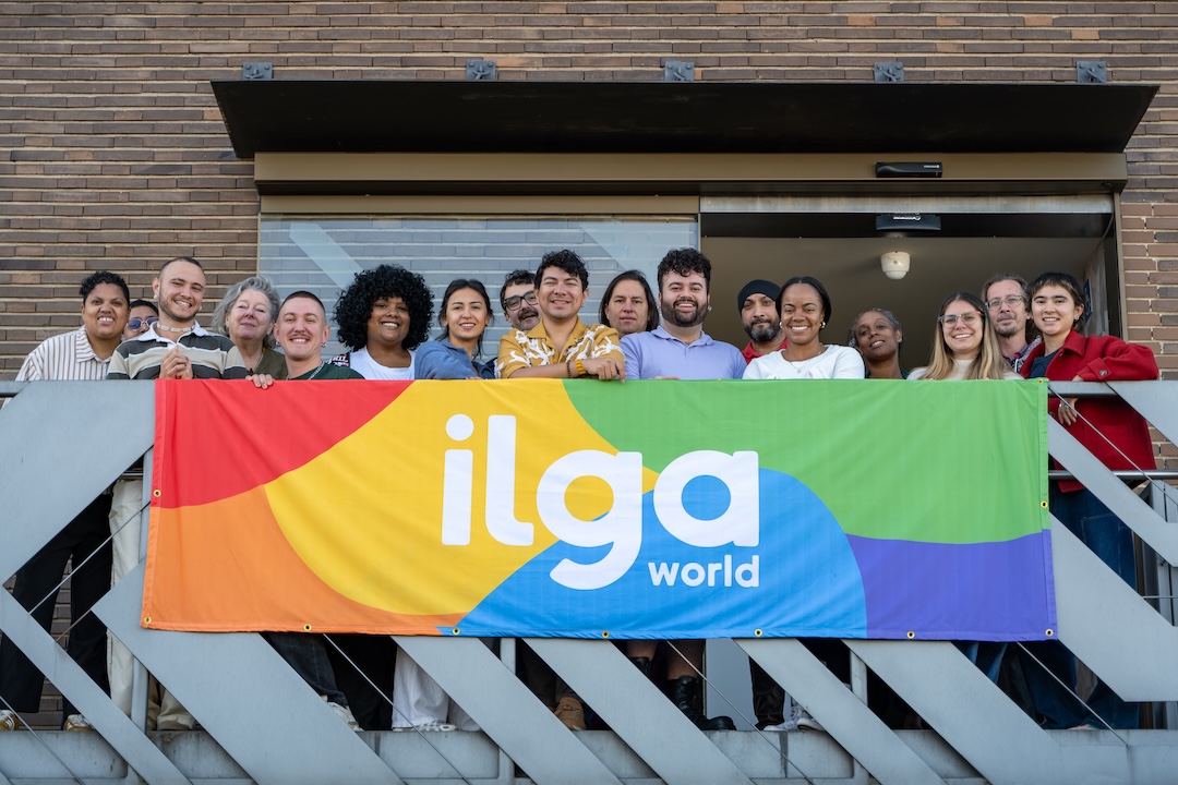 A group of people posing for a photo on a balcony, with a banner reading 