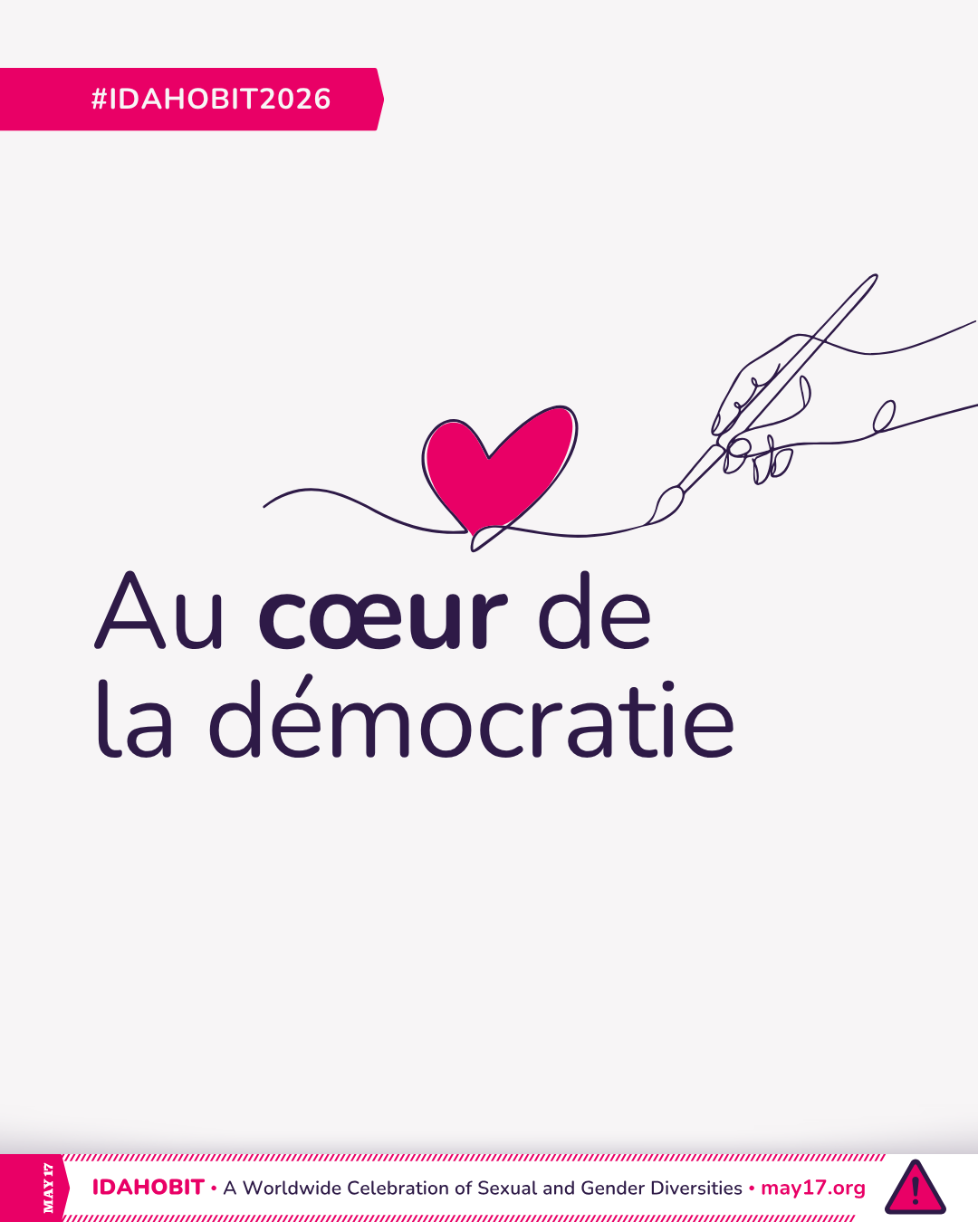 Dessin au trait représentant une main tenant un pinceau et dessinant un cœur. Au centre, on peut lire « Au cœur de la démocratie ». Une bannière rose en dessous comporte l'inscription « IDAHOBIT – Une célébration mondiale des diversités sexuelles et de genre – may17.org » ainsi que le logo IDAHOBIT, un triangle rose surmonté d'un point d'exclamation.