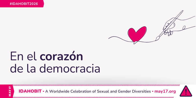 Arte lineal de una mano sosteniendo un pincel y dibujando un corazón. En el centro, el texto dice: “En el corazón de la democracia”. Una franja rosada debajo incluye "IDAHOBIT – Una celebración mundial de diversidades sexuales y de género – may17.org" y el isotipo de IDAHOBIT, un triángulo rosa con signo de exclamación.