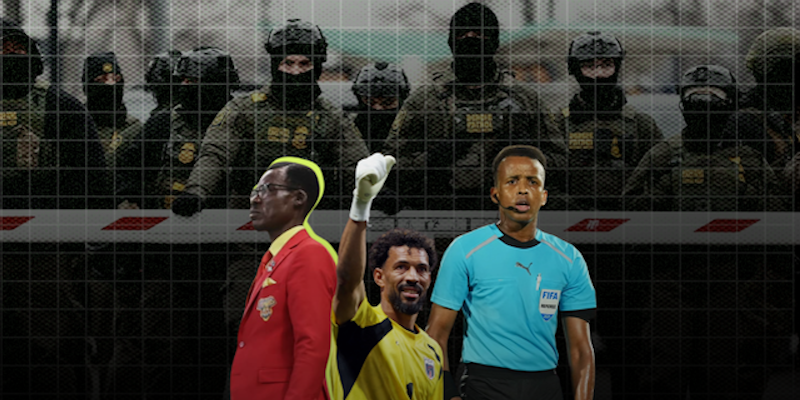Three men stand in front of a fence with uniformed, masked officers behind them; one man wears a red suit, one is in a goalkeeper uniform, and one wears a referee shirt.