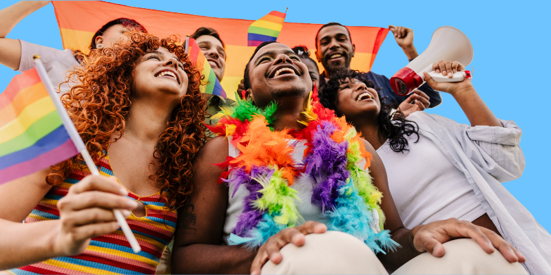 A group of diverse people holds Pride flags